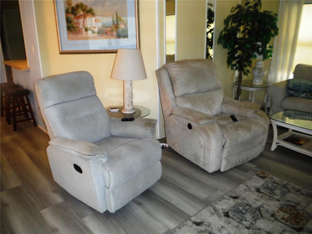 Two light-colored recliners sit on wood-look flooring in a living room with a table lamp — 98 SUGAR BEAR DRIVE UNIT 57, SAFETY HARBOR, FL