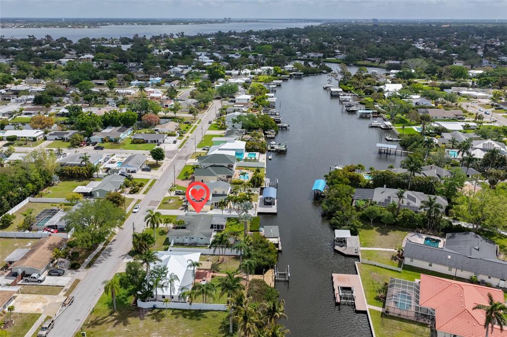 An aerial view shows a residential neighborhood with houses along a canal and street — 6907 9TH AVENUE NW, BRADENTON, FL