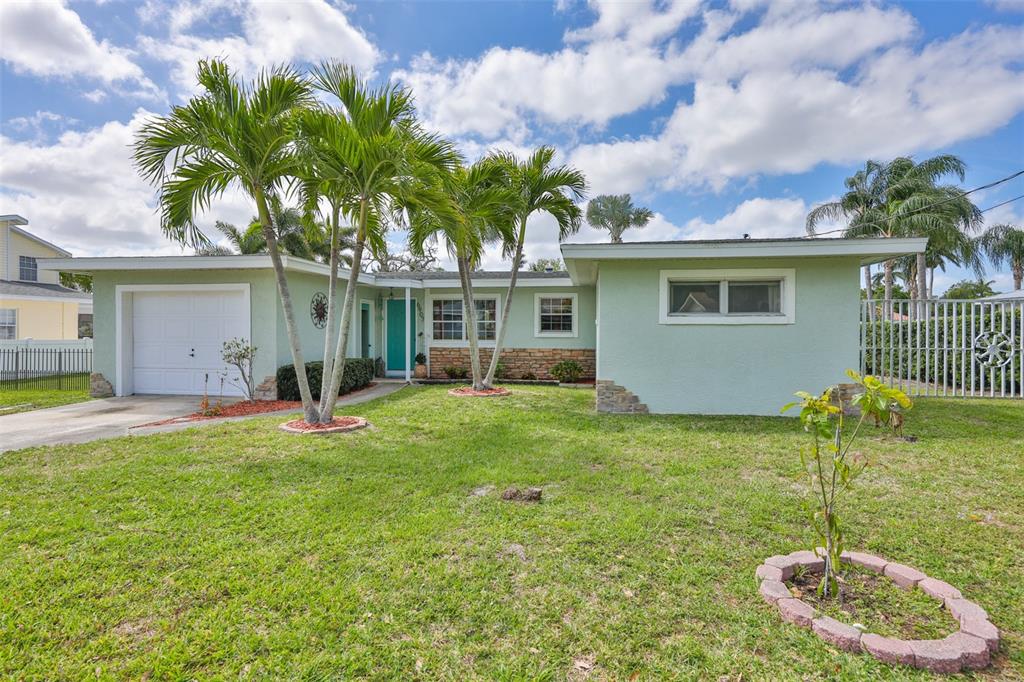 A light green single-story house features a white garage, palm trees, and a front lawn — 6907 9TH AVENUE NW, BRADENTON, FL