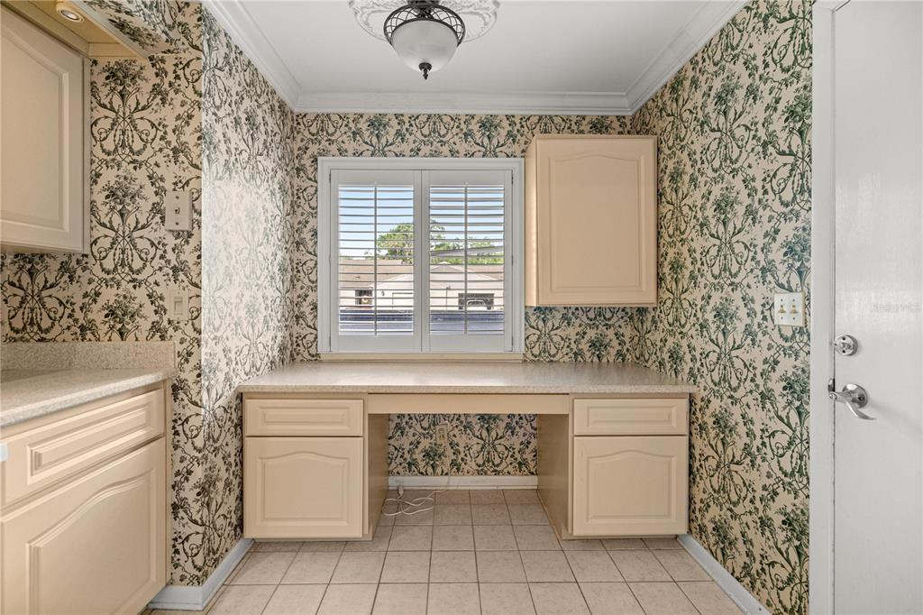 A kitchen nook features beige cabinetry, patterned wallpaper, a window with shutters, and tile flooring — 2050 SE 37TH COURT CIRCLE, OCALA, FL