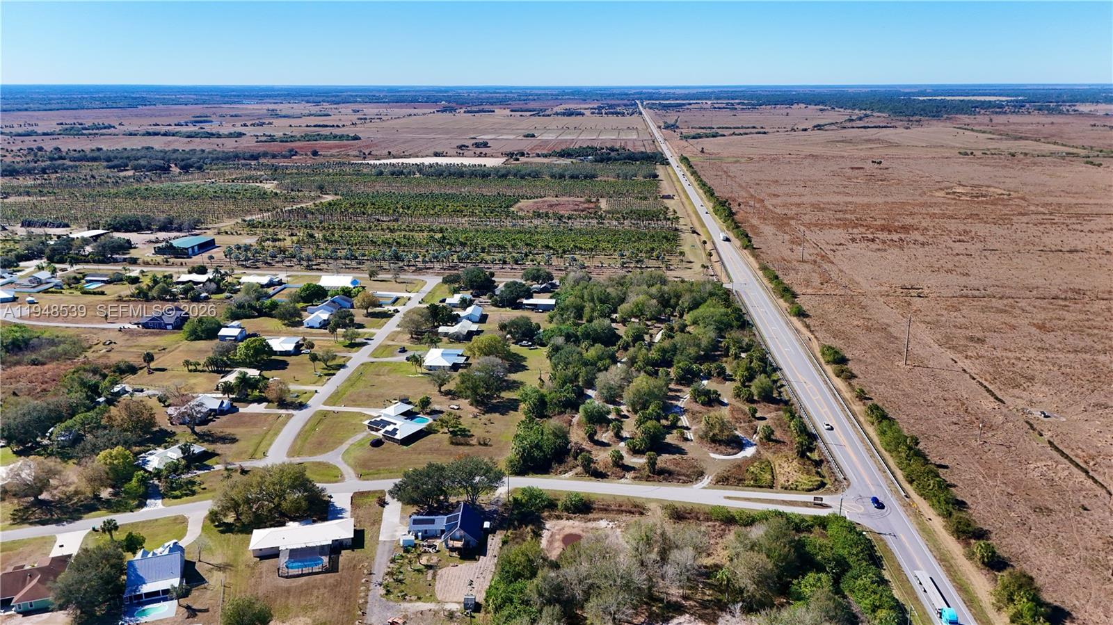 An aerial view shows a rural residential neighborhood situated next to a highway and fields — 8636 W Hwy 70, Okeechobee FL 34974, OKEECHOBEE, FL