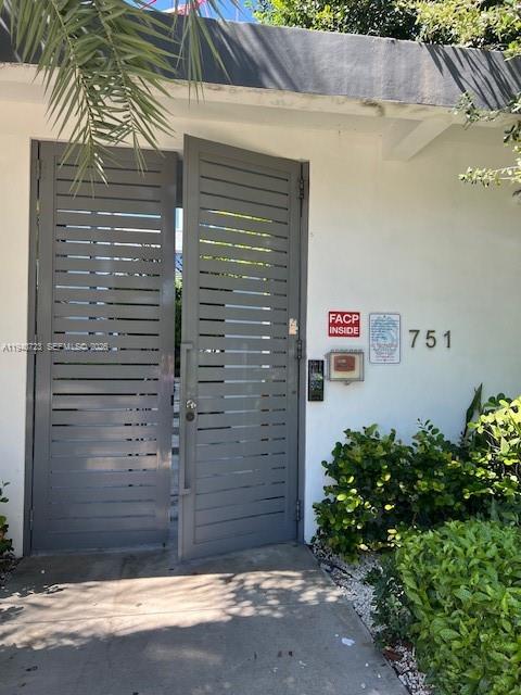 A gray slatted metal gate stands at the entrance of a white building — 751 NW 1st St # 305, Miami FL 33128, MIAMI, FL