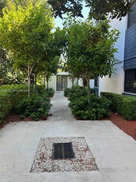 A concrete walkway leads toward a gated entrance flanked by trees and manicured hedges — 751 NW 1st St # 305, Miami FL 33128, MIAMI, FL