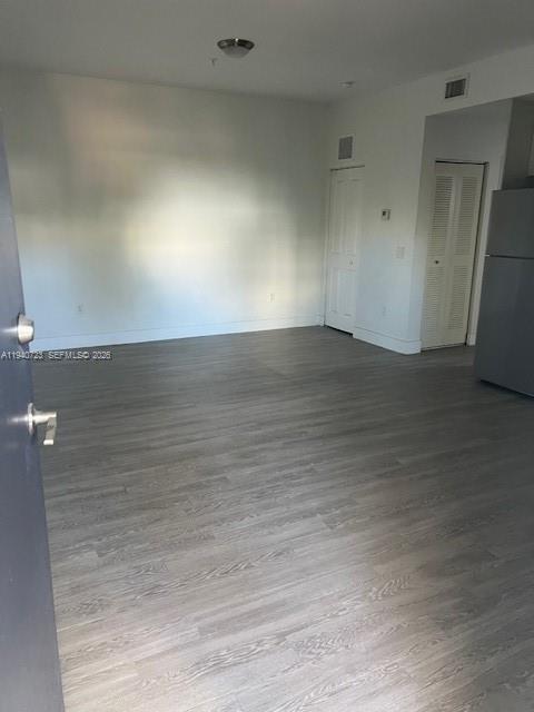 An empty room features light-colored wood-look flooring, white walls, and a stainless steel refrigerator — 751 NW 1st St # 305, Miami FL 33128, MIAMI, FL