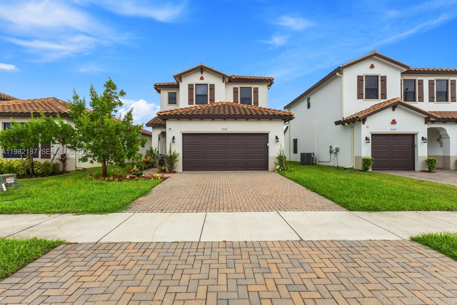 A two-story house with a brown garage door and a paved driveway under a blue sky — 5626 Agostino Way, Ave Maria FL 34142, AVE MARIA, FL