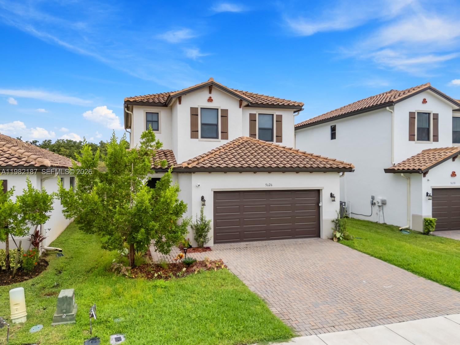 A two-story suburban house with a brown tile roof, white stucco walls, and a garage — 5626 Agostino Way, Ave Maria FL 34142, AVE MARIA, FL