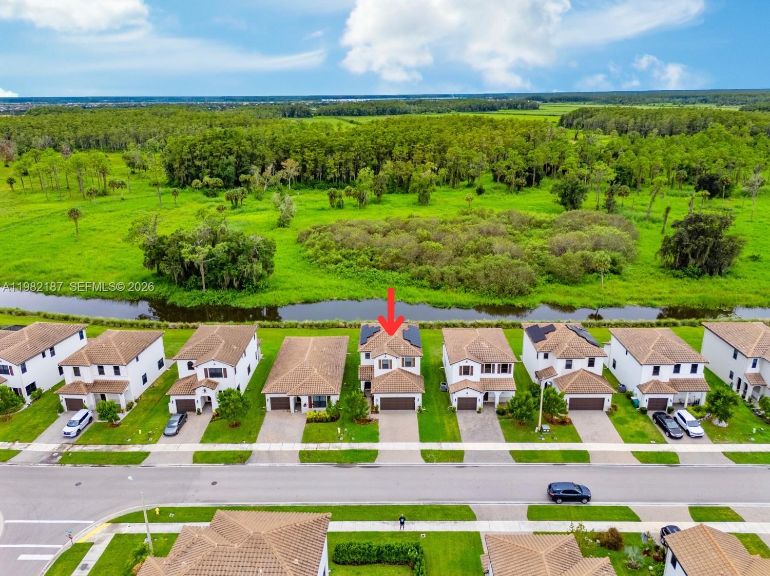 An aerial view shows a row of suburban houses with a red arrow pointing to one — 5626 Agostino Way, Ave Maria FL 34142, AVE MARIA, FL