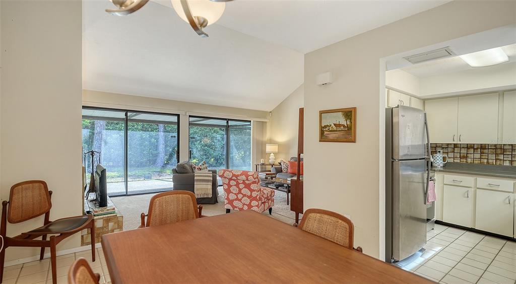 A dining area with a wooden table leads into a living room with sliding glass doors — 4983 GREENCROFT ROAD UNIT 181, SARASOTA, FL