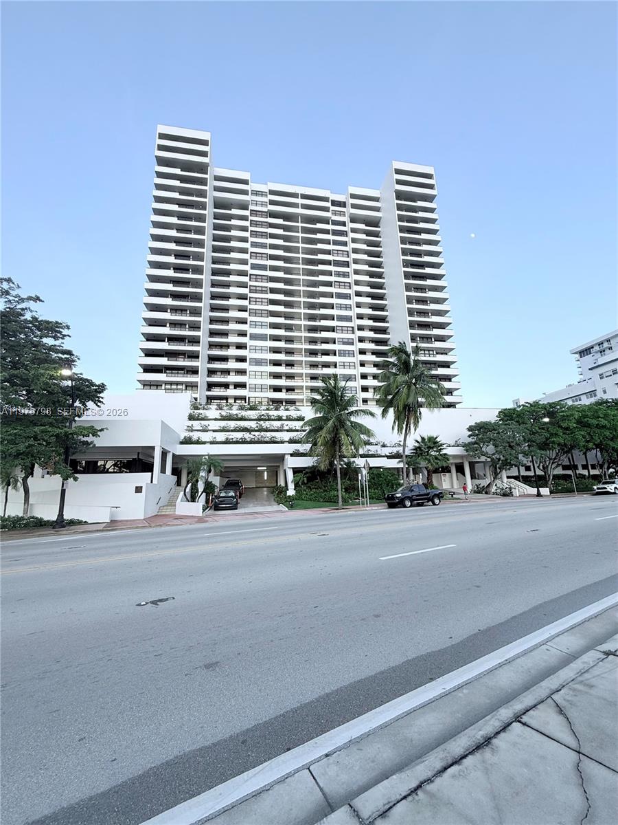 A tall white residential high-rise building stands behind a street with palm trees — 2555 Collins Ave # 506, Miami Beach FL 33140, MIAMI BEACH, FL