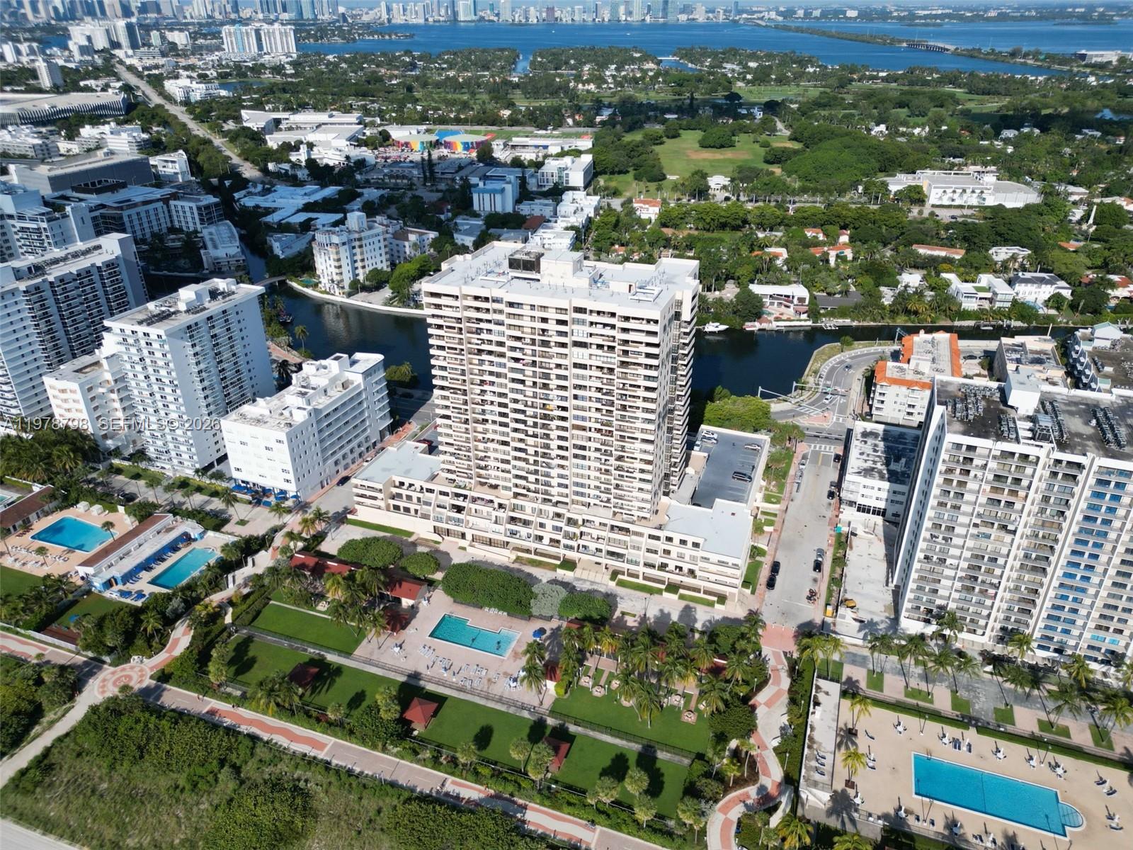 An aerial view shows a tall residential building surrounded by swimming pools and green spaces — 2555 Collins Ave # 506, Miami Beach FL 33140, MIAMI BEACH, FL
