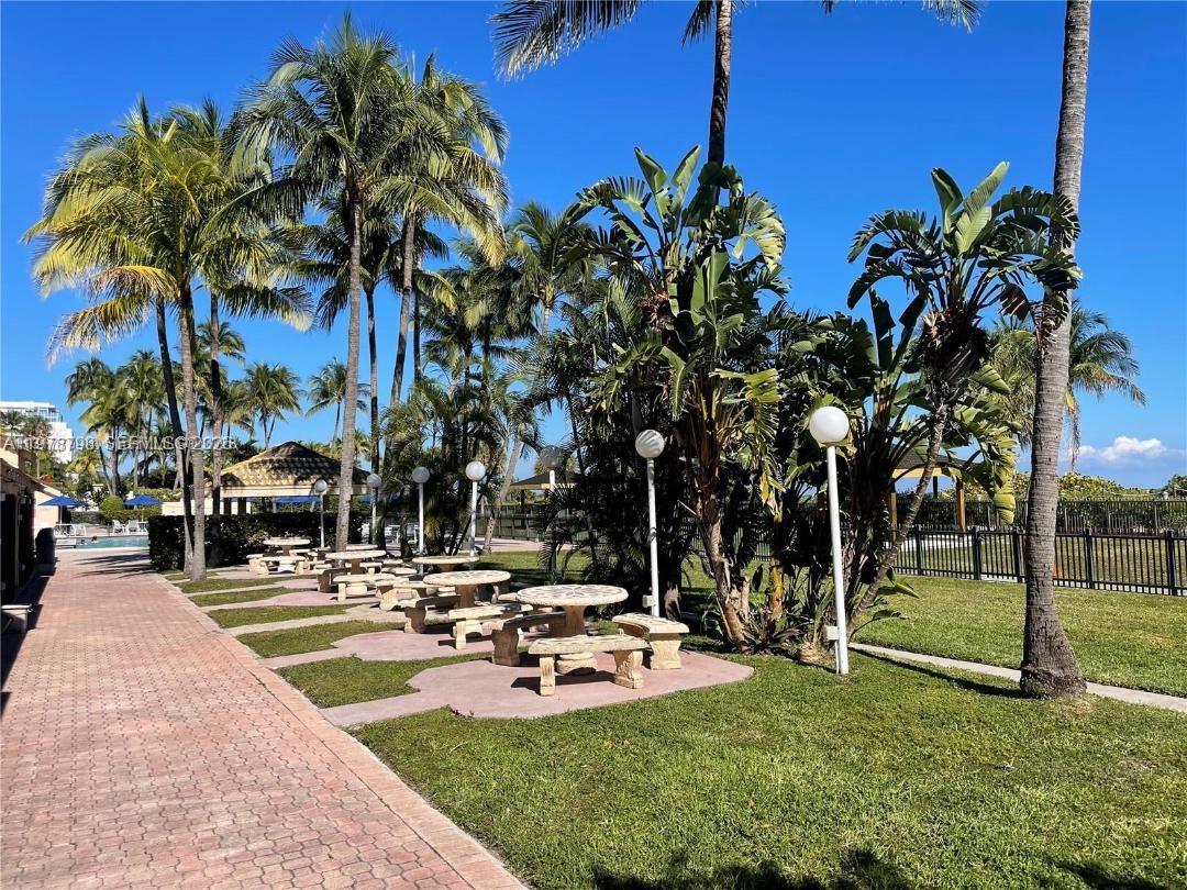 A paved walkway leads past several stone picnic tables shaded by palm trees and foliage — 2555 Collins Ave # 506, Miami Beach FL 33140, MIAMI BEACH, FL