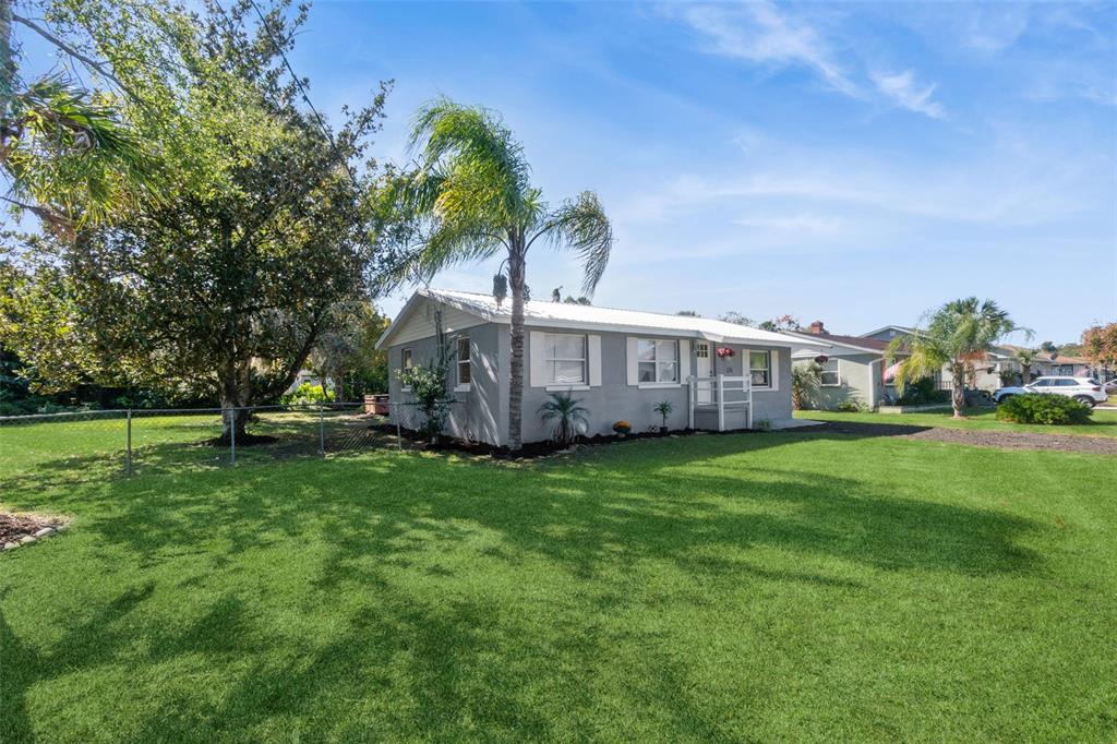 A gray single-story house with a white roof sits on a large, grassy lawn — 126 KENSINGTON ROAD, DELAND, FL