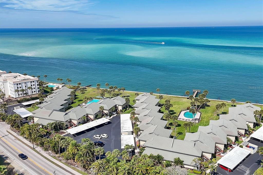 An aerial view shows a coastal condominium complex with multiple buildings, swimming pools, and parking — 4660 OCEAN BOULEVARD UNIT Q2, SARASOTA, FL
