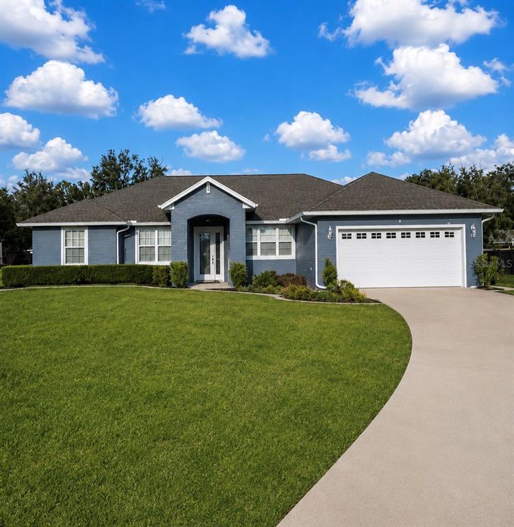 A blue brick single-story house with a white garage door and a curved concrete driveway — 360 NW 113TH CIRCLE, OCALA, FL