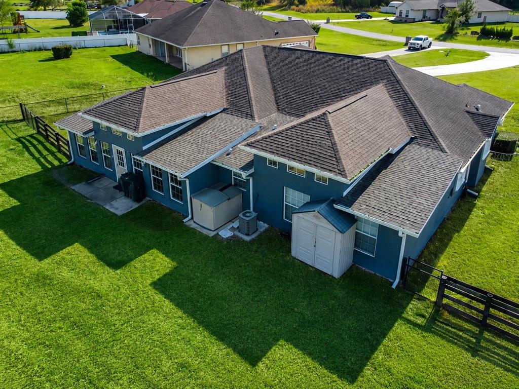 An aerial view shows the rear exterior of a blue house with a shingled roof — 360 NW 113TH CIRCLE, OCALA, FL