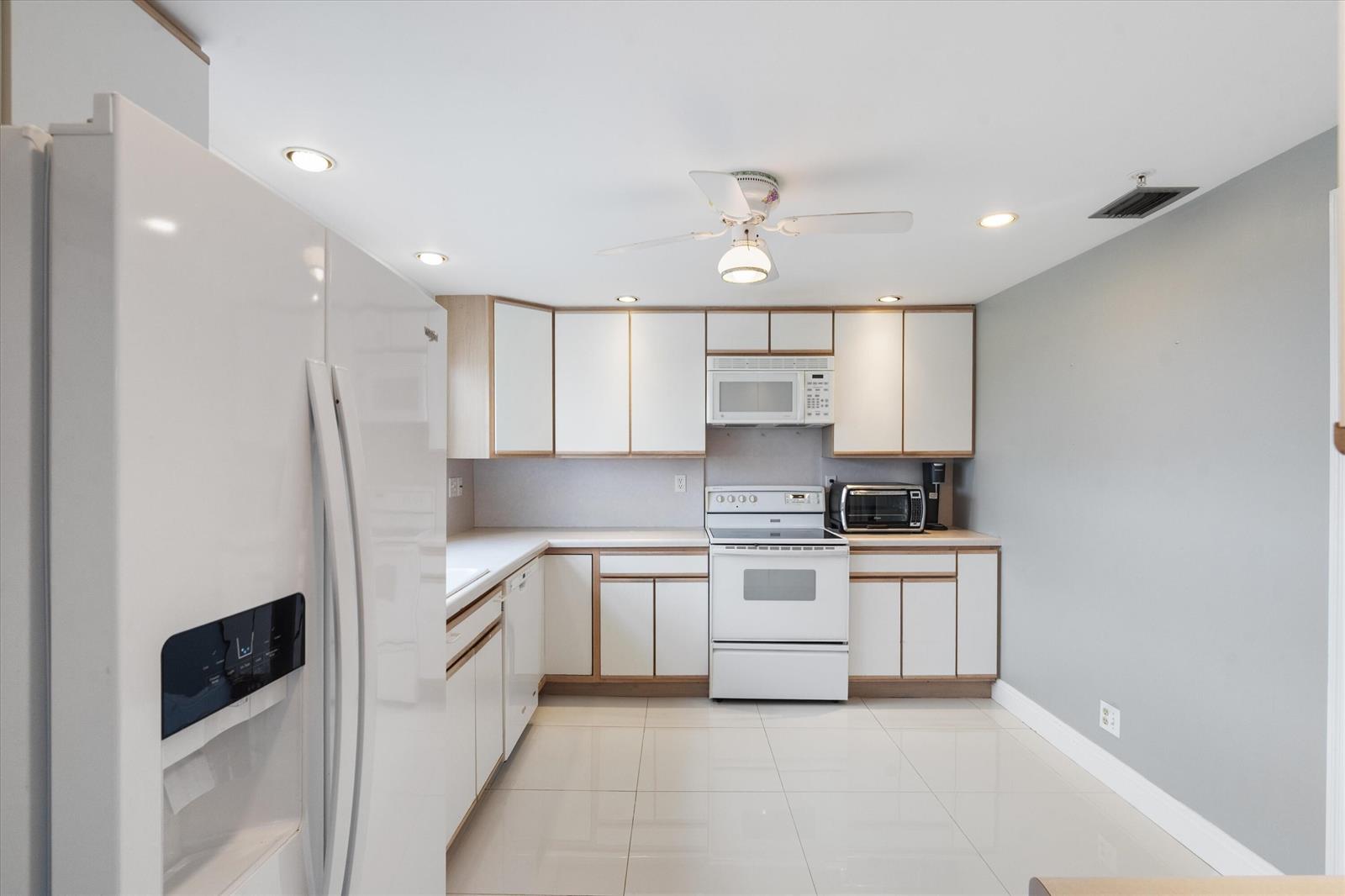 A kitchen with white cabinets, white appliances, light tile flooring, and gray walls — 3300 S Ocean Boulevard # c, Highland Beach FL 33487, HIGHLAND BEACH, FL