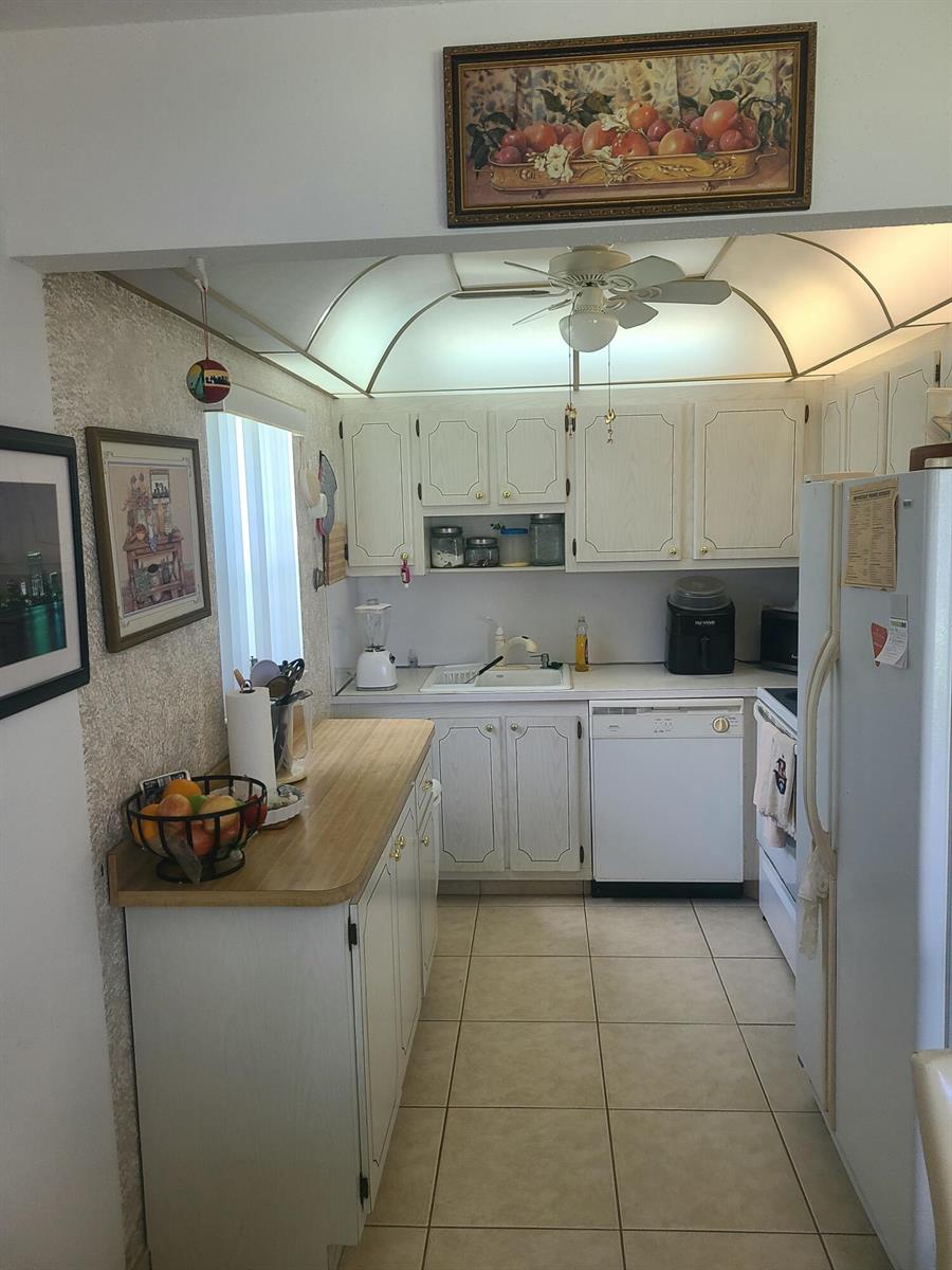 A kitchen features white cabinets, a light-colored countertop, tile flooring, and a ceiling fan — 257 Brittany F # 257, Delray Beach FL 33446, DELRAY BEACH, FL
