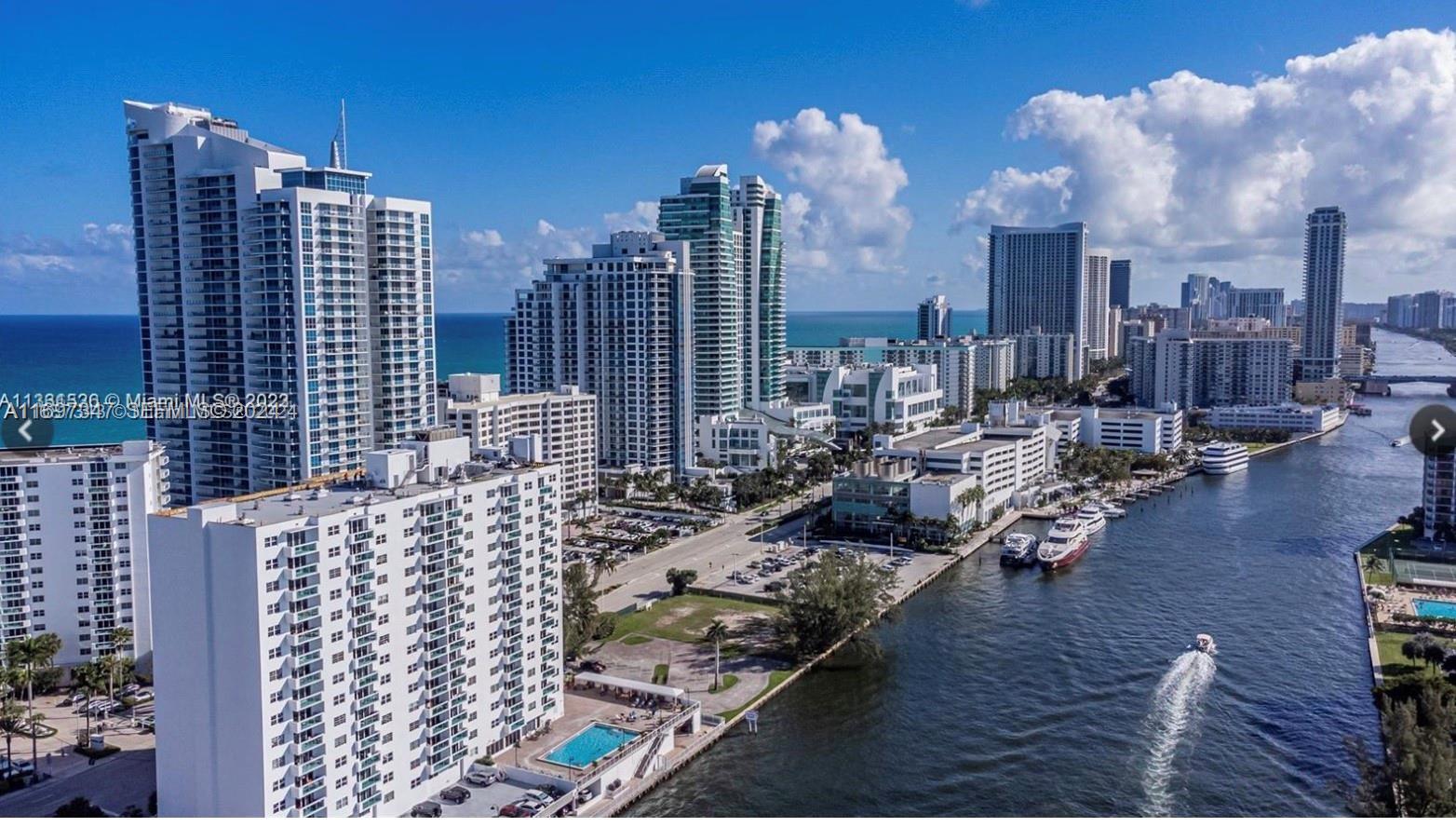 An aerial view of high-rise apartment buildings along a waterway with boats and a pool — 3000 S Ocean Dr # 1012, Hollywood FL 33019, HOLLYWOOD, FL