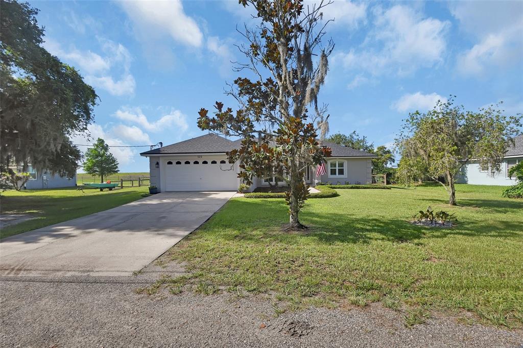 A single-story house with a white garage door, a concrete driveway, and a large front yard — 523 KONOMAC LAKE DRIVE, DEBARY, FL