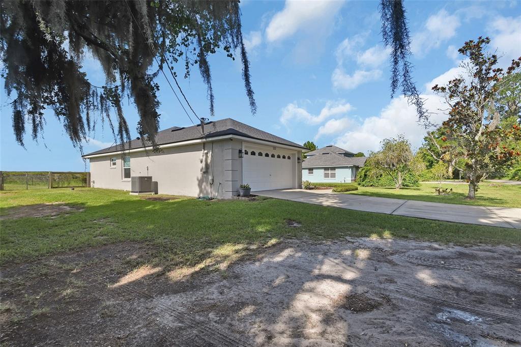 A side view of a single-story house with a white garage door and a concrete driveway — 523 KONOMAC LAKE DRIVE, DEBARY, FL