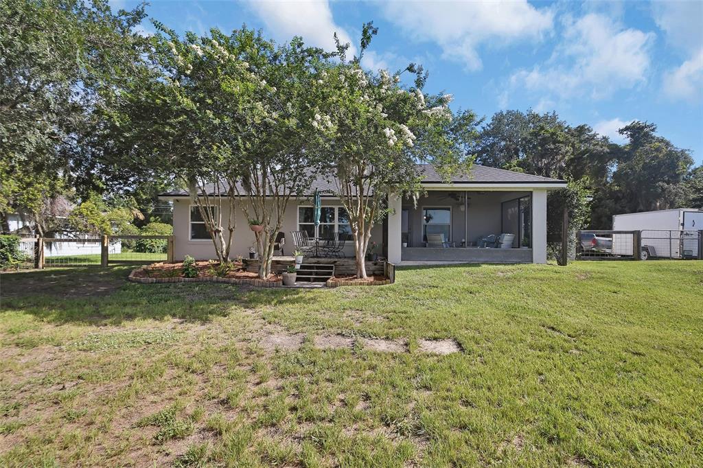 The backyard of a house features a screened-in porch, a small deck, and mature trees — 523 KONOMAC LAKE DRIVE, DEBARY, FL
