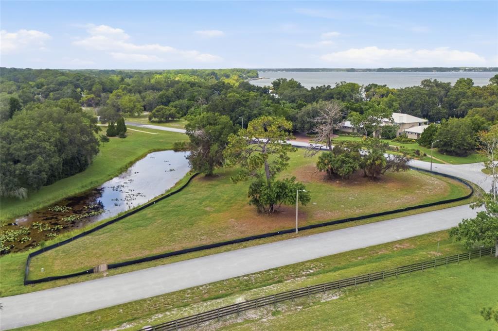 An aerial view shows a grassy lot with a pond, trees, and surrounding paved roads — 520 AUSTIN DRIVE, TARPON SPRINGS, FL