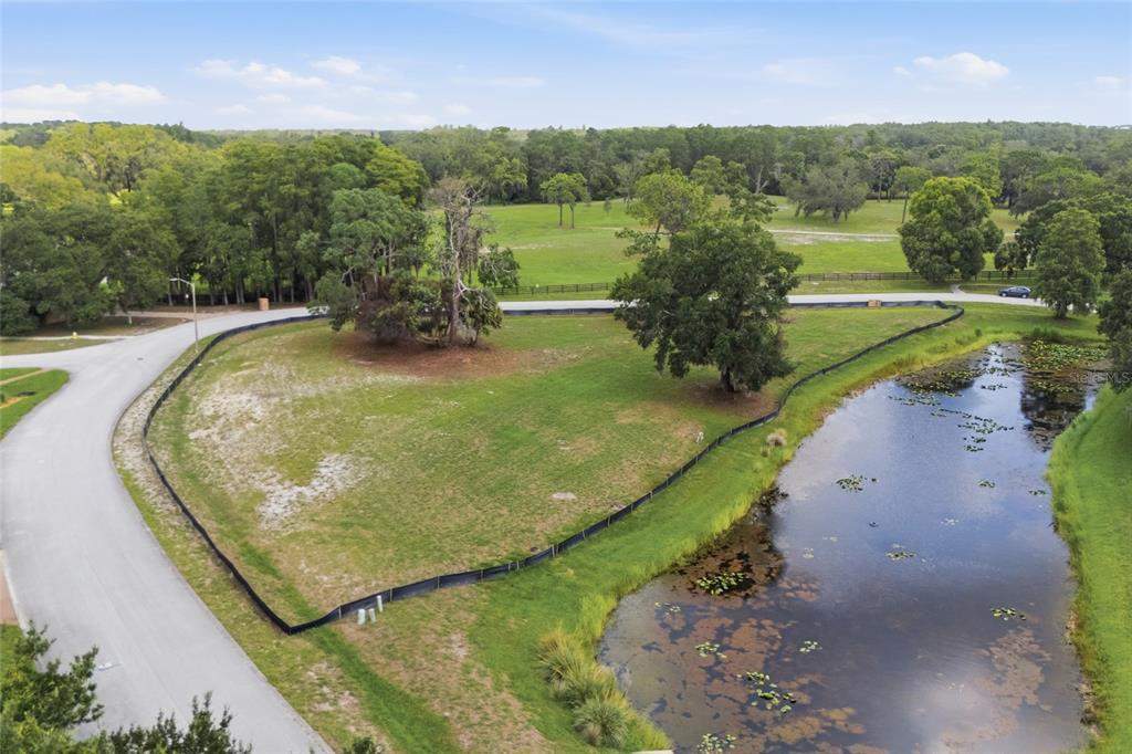 An aerial view shows a vacant, grassy lot bordered by a road and a pond — 520 AUSTIN DRIVE, TARPON SPRINGS, FL