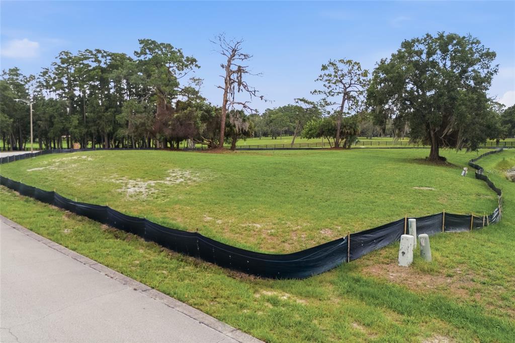 A vacant, grassy residential lot is enclosed by black silt fencing along a paved road — 520 AUSTIN DRIVE, TARPON SPRINGS, FL