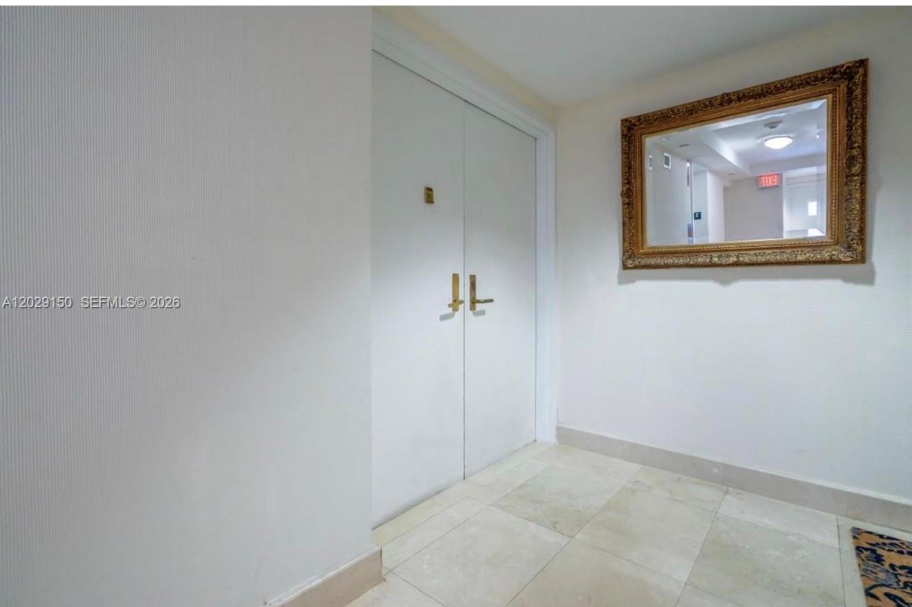 A hallway features white double doors, light-colored tile flooring, and a large ornate gold mirror — 151 SE 15th Rd # 502, Miami FL 33129, MIAMI, FL