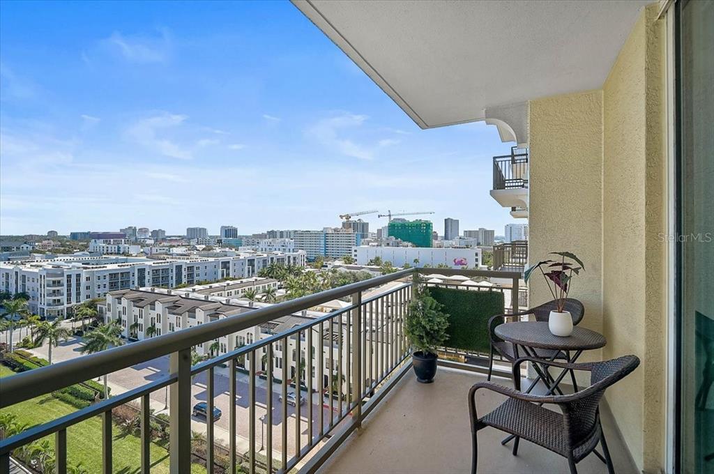 A high-rise balcony features a small table, two chairs, and a view of the city — 800 N TAMIAMI TRAIL UNIT 910, SARASOTA, FL