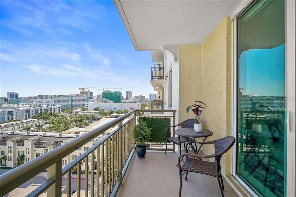 A balcony with a small table and two chairs overlooks a city skyline — 800 N TAMIAMI TRAIL UNIT 910, SARASOTA, FL