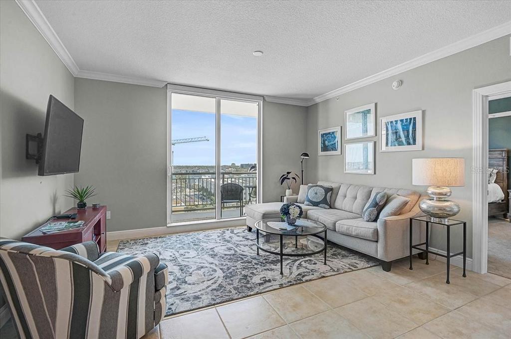 A living room features a grey sectional sofa, a striped armchair, and a balcony view — 800 N TAMIAMI TRAIL UNIT 910, SARASOTA, FL