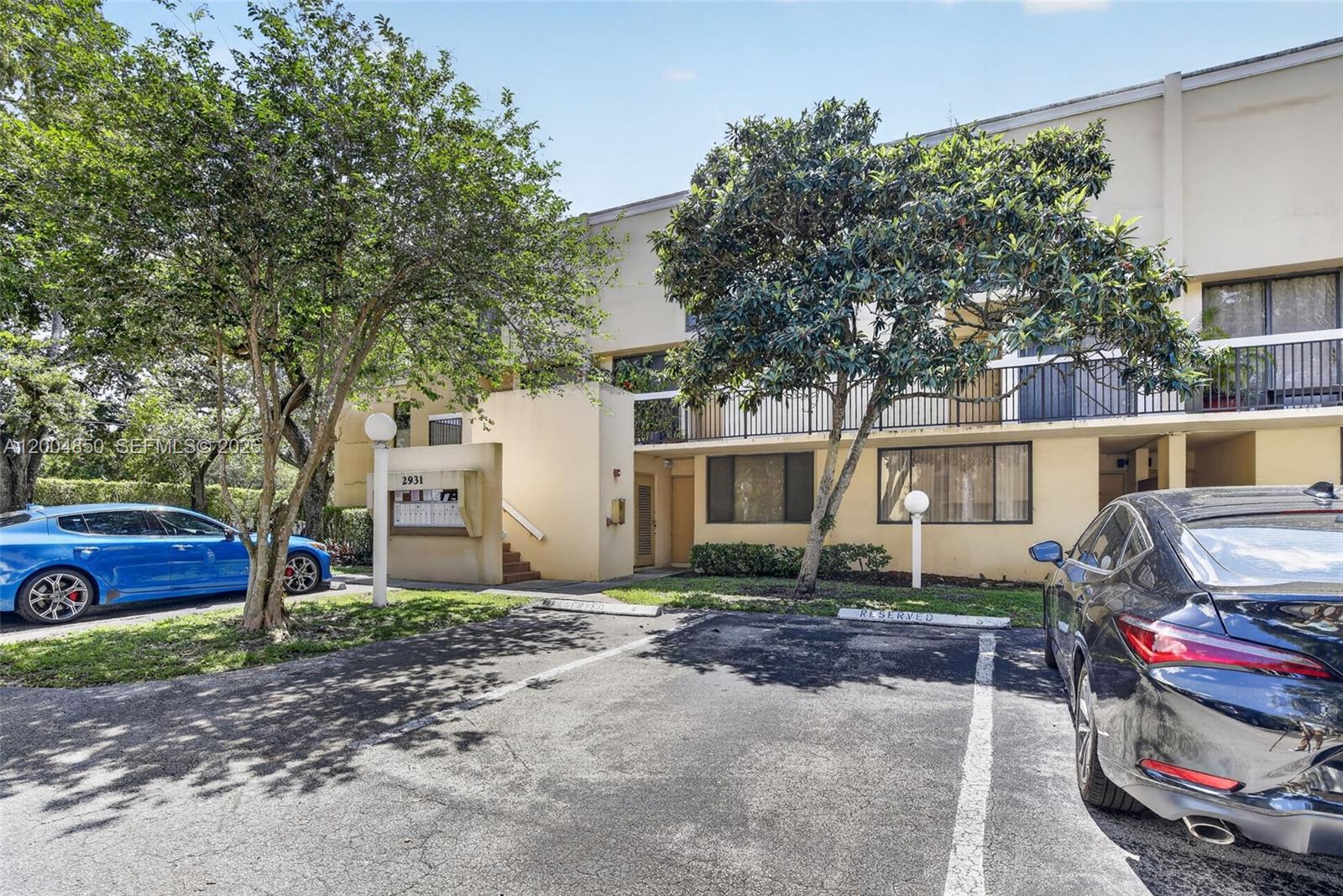 A two-story apartment building exterior features a parking lot, trees, and a mailbox kiosk — 2931 SW 87th Ter # 1913, Davie FL 33328, DAVIE, FL