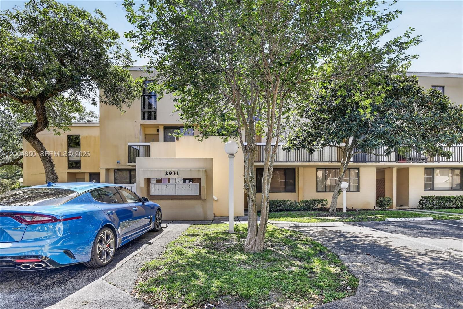 A blue car is parked in front of a multi-story apartment building with mailboxes — 2931 SW 87th Ter # 1913, Davie FL 33328, DAVIE, FL