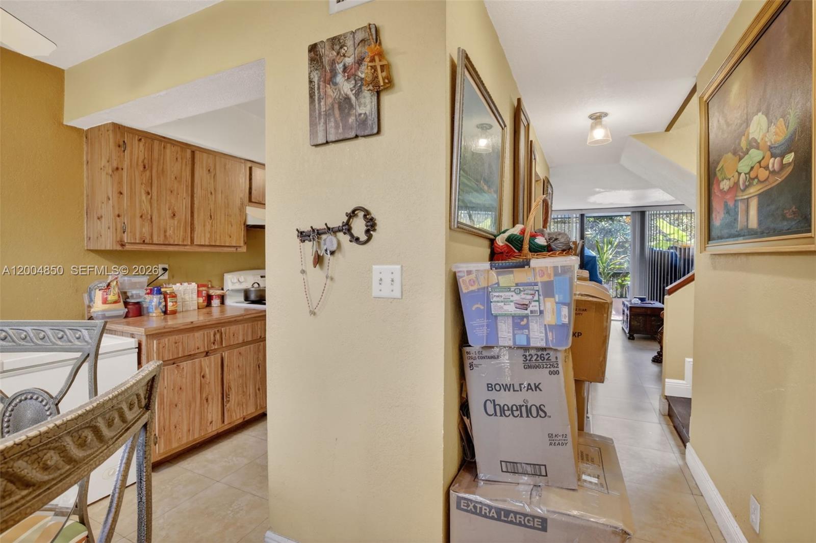 A kitchen with wood cabinets is adjacent to a hallway filled with stacked cardboard boxes — 2931 SW 87th Ter # 1913, Davie FL 33328, DAVIE, FL
