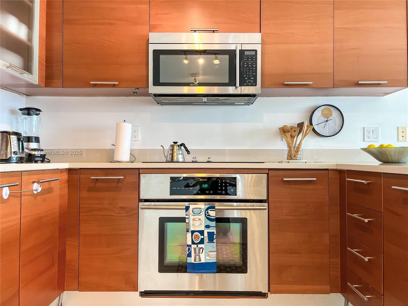 A kitchen features wood cabinets, stainless steel appliances, and a light-colored countertop — 3250 NE 1st Ave # 708, Miami FL 33137, MIAMI, FL