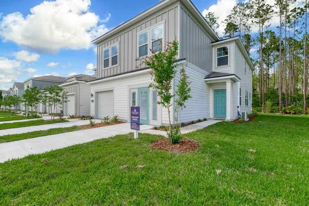 A two-story house with white and gray siding, a teal front door, and a concrete driveway — 10723 WATERFIELD ROAD, JACKSONVILLE, FL