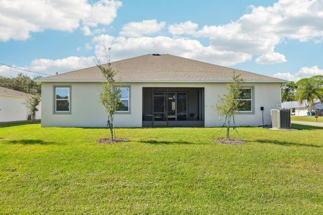The back exterior of a single-story house features a screened-in porch and a grassy yard — 30513 PRESTWICK AVENUE, SORRENTO, FL