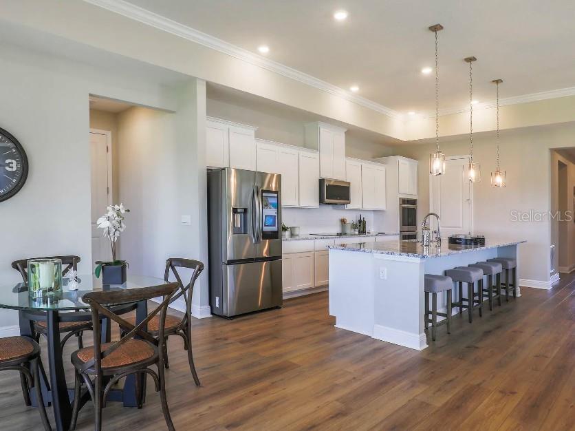 A kitchen with white cabinets, stainless steel appliances, and a large island with bar seating — 30513 PRESTWICK AVENUE, SORRENTO, FL