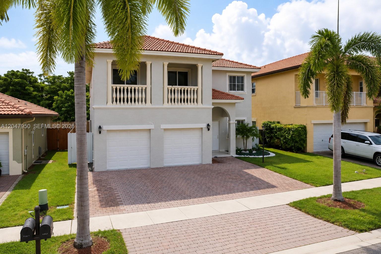 A two-story house with a tiled roof, two-car garage, and a balcony above — 1351 NE 41st Pl, Homestead FL 33033, HOMESTEAD, FL