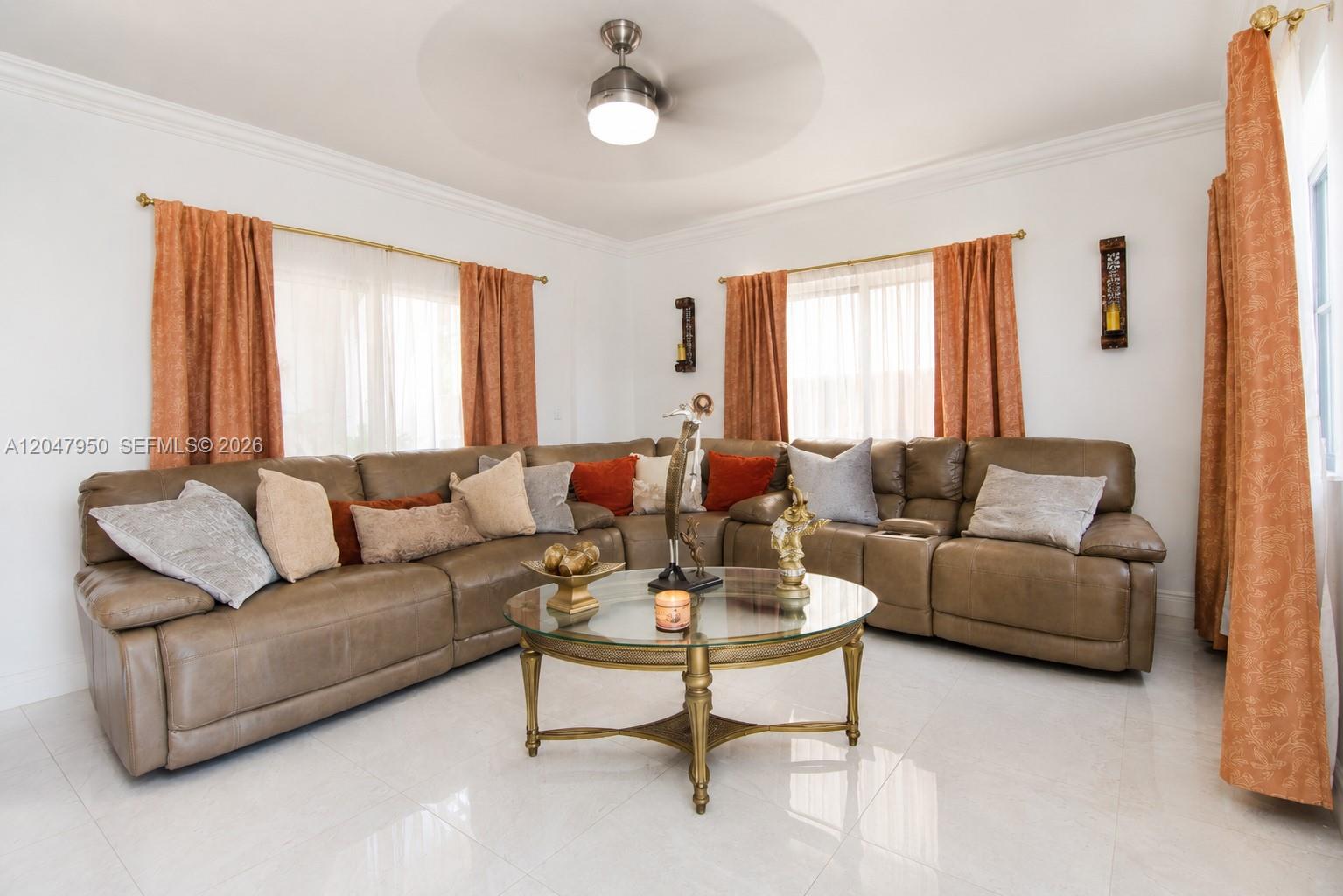 A living room features a large brown sectional sofa, a glass coffee table, and orange curtains — 1351 NE 41st Pl, Homestead FL 33033, HOMESTEAD, FL