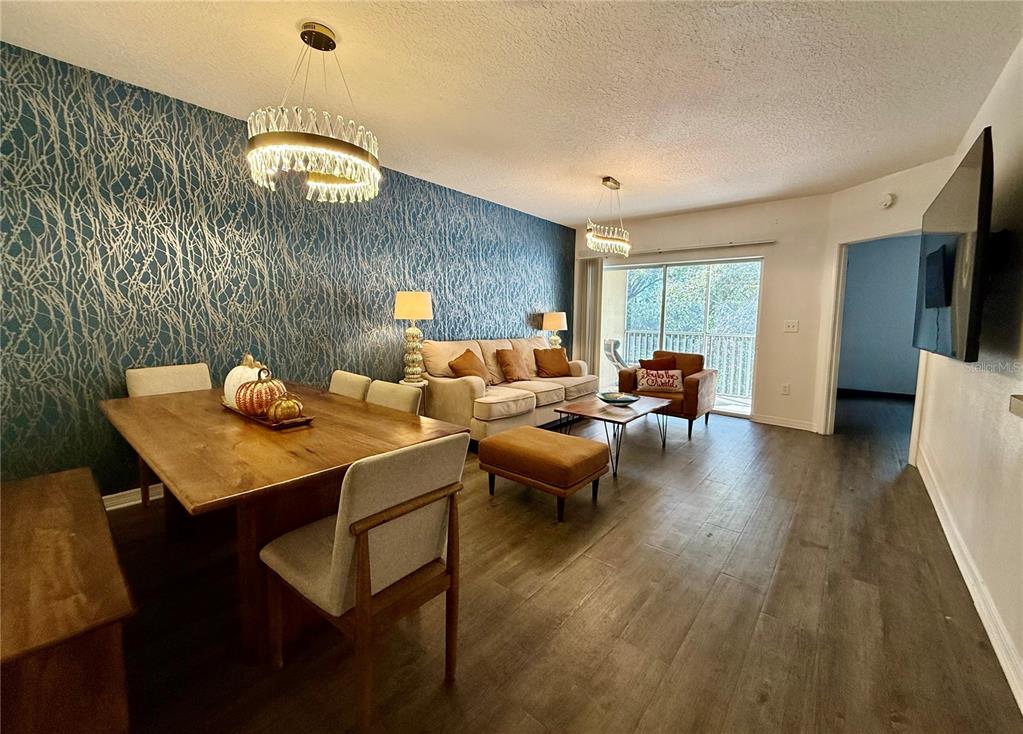 A living and dining room features a blue accent wall, wood flooring, and two chandeliers — 6447 CYPRESSDALE DRIVE UNIT 201, RIVERVIEW, FL