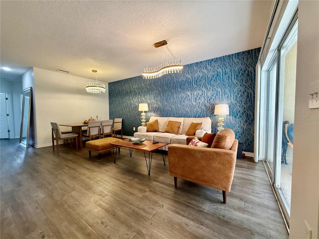 A living and dining area features a blue accent wall, wood-look flooring, and modern lighting — 6447 CYPRESSDALE DRIVE UNIT 201, RIVERVIEW, FL