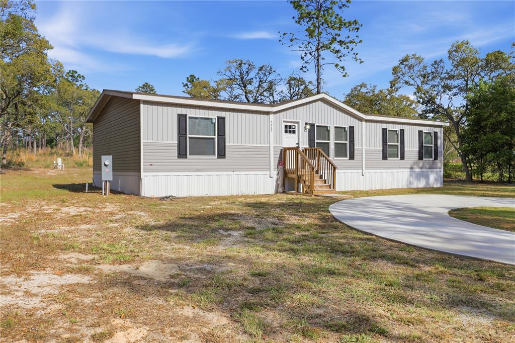 A single-story manufactured home with grey siding and a wooden front porch sits on land — 4959 SW 178TH TERRACE, DUNNELLON, FL