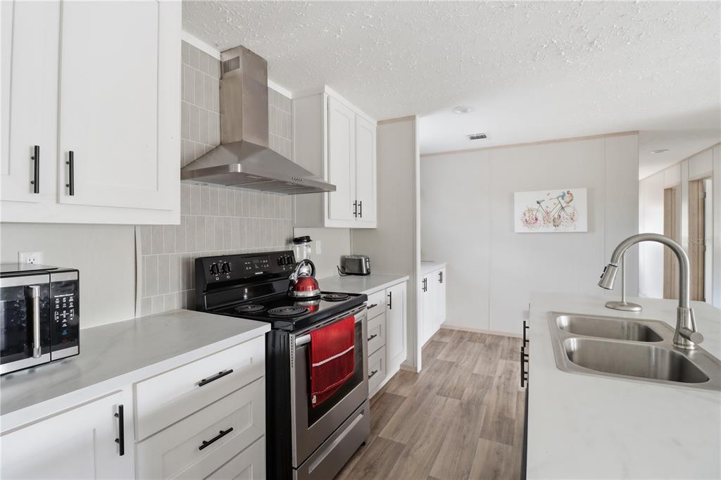 A modern kitchen features white cabinets, stainless steel appliances, a tile backsplash, and an island — 4959 SW 178TH TERRACE, DUNNELLON, FL