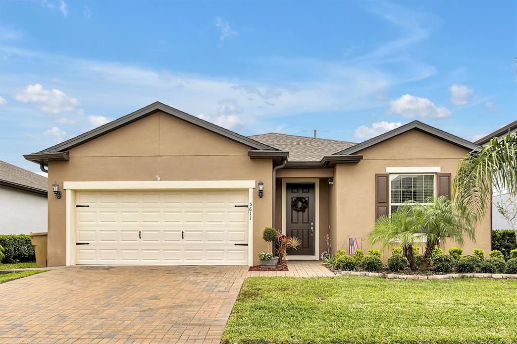 A single-story house with a tan stucco exterior, a two-car garage, and a paved driveway — 5611 BARLETTA DRIVE, ST CLOUD, FL