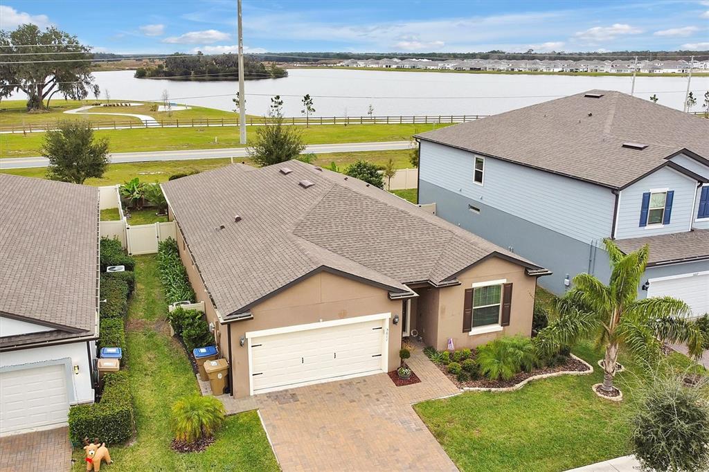 An aerial view shows a single-story house with a paved driveway and a lake view — 5611 BARLETTA DRIVE, ST CLOUD, FL