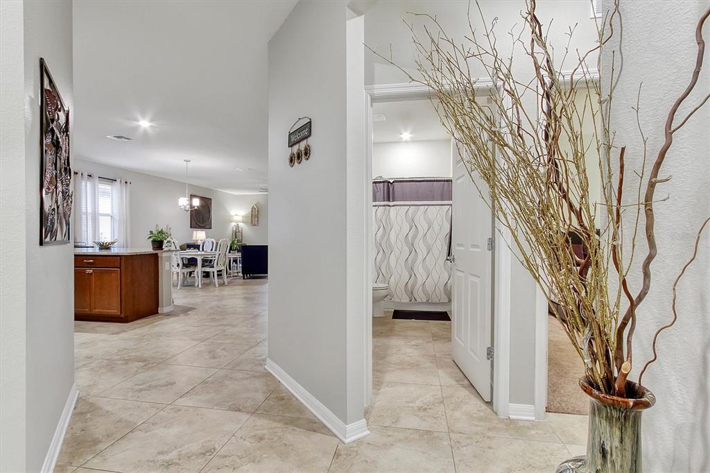 A tiled hallway leads to a bathroom and an open-concept kitchen and dining area — 5611 BARLETTA DRIVE, ST CLOUD, FL