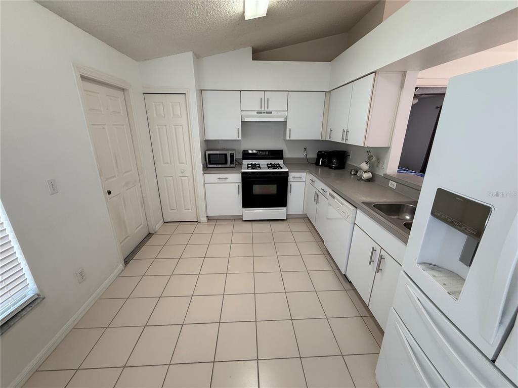 A kitchen with white cabinets, white appliances, and light-colored tile flooring — 11755 FOXGLOVE DRIVE, CLERMONT, FL