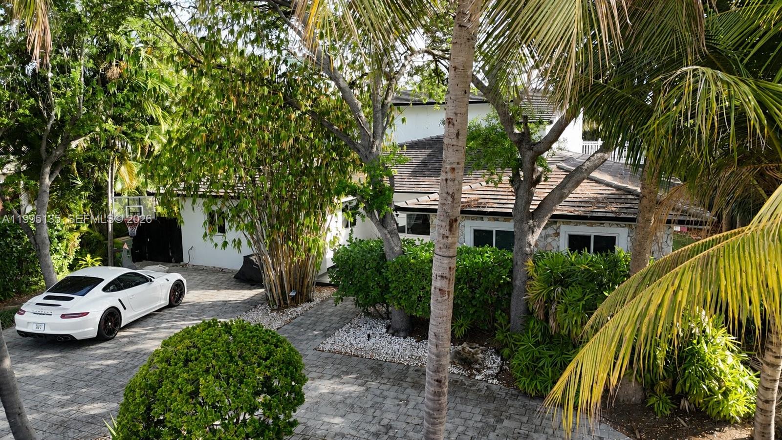 A white sports car is parked on a paved driveway in front of a house — 1895 NE 118th Rd, North Miami FL 33181, NORTH MIAMI, FL